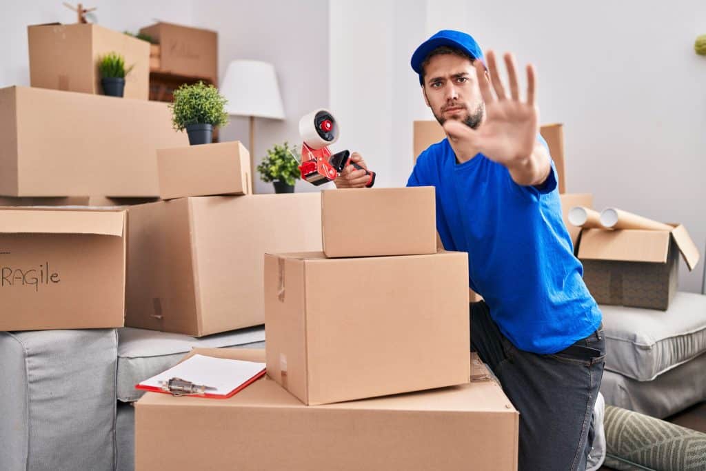 removalist with beard working moving boxes with open hand doing stop sign with serious and confident expression, defense gesture