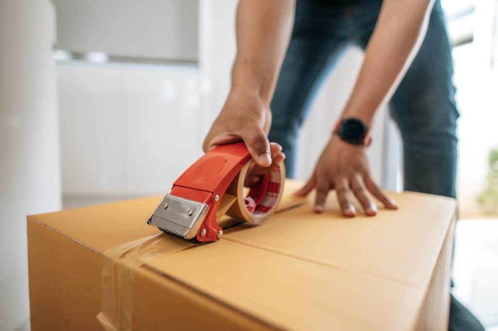 Male hand sealing big box with glue tape for packing